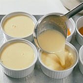Cream being poured with ladle in ramekins