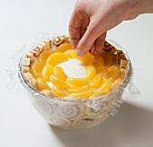Mandarin orange pieces being arranged on cream in bowl