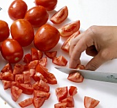 Tomatoes being chopped with knife on cutting board, step 1