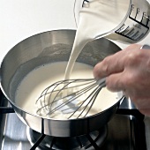 Milk being added and whisked while preparing mornay sauce, step 2
