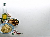 Spaghetti with chilli, olive oil bottle and garlic on white background, copy space