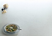 Bowl of minestrone soup and fresh parmesan on white background, copy space