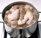 Chicken pieces being boiled in casserole while preparing chicken broth, step 1