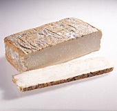 Taleggio cheese and one slice of it on white background