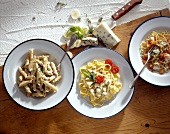 Different types of pasta dishes with cheeses on plates