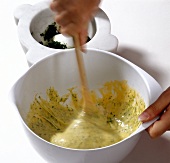 Hand mixing herb spaetzle in bowl, step 1