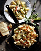 Rigatoni with zucchini in pan and penne with peas on plate