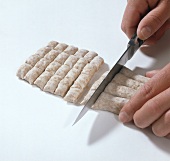 Dough being cut into pieces with knife while preparing trofie, step 2