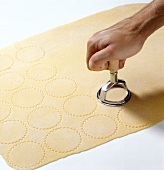 Hand cutting pasta dough with round cutter for preparation of tortelloni, step 1