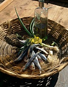 Basket of sardines, spring onions and olive oil on wooden table