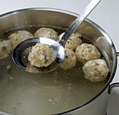 Dumplings being removed from water while preparing porcini mushroom dumplings, step 4