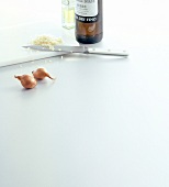 Whole onions, chopped onion, knife, cutting board and bottle of sherry on white background