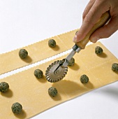 Pasta dough with meat balls being cut with pastry cutter