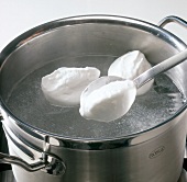 Egg white dumplings being cooked in boiling water