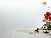 Pasta, herbs, flour, tomatoes, cheese and pastry wheel on white background, copy space