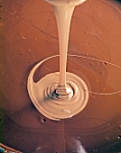 Close-up of liquid chocolate being poured in melted dark chocolate, book of chocolate