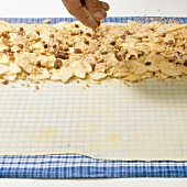 Toasted breadcrumbs and nuts topped on greased dough sheet for preparing strudel