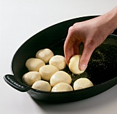 Dough balls being rolled in melted butter