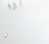 Four whole eggs and one halved egg on white background