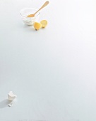 Egg shell, halved lemon and bowl of curd with wooden spoon on white background, copy space