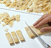 Quadrucci pasta being cut into strips and squares
