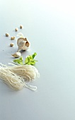 Garlic bulb and raw rice noodles on white background