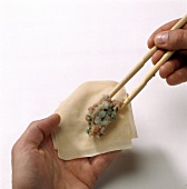 Filling being placed on pasta sheet with chopsticks for preparation of won-tans, step 1