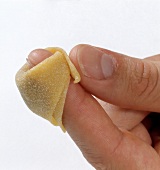 Corners of stuffed pasta sheet being pressed for preparing tortellini, step 2
