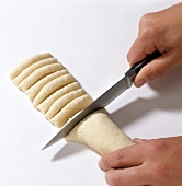 Roll being cut into pieces with knife while preparing pasta, step 9