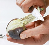 Close-up of fig being peeled with knife
