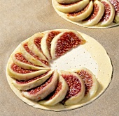 Slices of figs being arranged on puff pastry