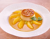 Cream caramel with orange pieces, grapes and mint leaves on plate