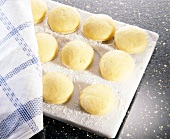 Round yellow dough in row with cloth on floured board