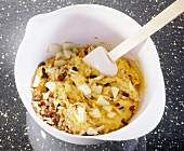 Choux pastry dough with walnuts, raisins and apple cubes in bowl