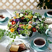 Blumenkranz aus frischen Blumen in Kuchenform als Tischdeko, bunt