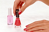 Close-up of woman opening red nail polish bottle