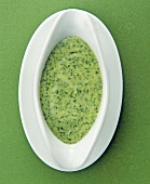 Kräutersoße mit Milch, Teller weiß, Hintergrund grün