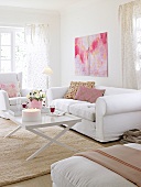 Living room with white sofa, cushions, wing chair, coffee table and wall painting
