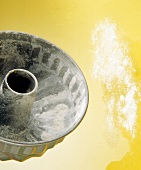 Baking gugelhupf vessel and flour on yellow background