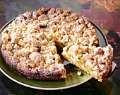 Close-up of almond crumble cake on plate with one piece on cake server