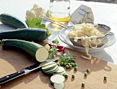 Pasta noodles in sieve and zucchini on wooden cutting board with knife