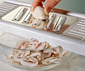 Close-up of mushrooms being sliced into thin slices with a vegetable slicer