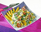 Close-up of rice salad with mango, green onions and ham