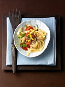 Ribbon pasta with tomato, eggplant and vegetables on white plate with wooden fork