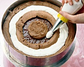 Cake being iced with chocolate cream and cream
