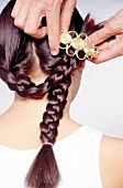 Rear view of woman with golden clasp being pinned up in braided hair