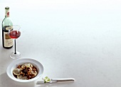 Tortellini with braised oxtail and glass of red wine on white background, copy space