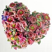 Ein herzförmiges Blumengesteck in rosa mit Rosen und Tausendschön
