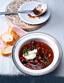 Goulash soup with black beans and bread slices in bowl