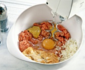 Meat, eggs, diced onions and mustard duch mixed in bowl with blender